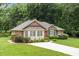 Charming single-story brick home featuring a lush front yard, well-maintained landscaping, and a covered front porch at 143 Cedarwood Dr, Henderson, NC 27536