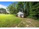 Exterior view of the charming outbuilding nestled amid a lush green yard, complemented by mature trees for privacy at 143 Cedarwood Dr, Henderson, NC 27536