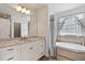 Bright bathroom featuring a vanity with marble countertop, tub, and a decorative window at 180 Normandy Rd, Louisburg, NC 27549
