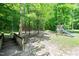 Lush backyard scene featuring a wooden bridge, vibrant greenery, and a playground set at 1826 Fillmore Dr, Creedmoor, NC 27522