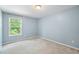 Inviting bedroom with light blue walls, large window with blinds, and neutral carpet flooring at 1826 Fillmore Dr, Creedmoor, NC 27522