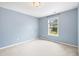 Comfortable bedroom with light blue walls, plush carpeting, and a bright window overlooking the front yard at 1826 Fillmore Dr, Creedmoor, NC 27522