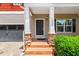 Inviting front porch with stone-based columns, a black front door, and landscaped bushes at 1826 Fillmore Dr, Creedmoor, NC 27522