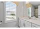 Bright bathroom featuring a white vanity, quartz countertop, and a large mirror reflects natural light from the window at 208 Jones Hill Rd, Holly Springs, NC 27540