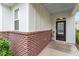 Welcoming front porch with a dark front door, brick facade, and cozy decor at 208 Jones Hill Rd, Holly Springs, NC 27540