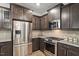 This kitchen features stainless steel appliances, granite counters, tile backsplash, and dark brown cabinetry at 208 Jones Hill Rd, Holly Springs, NC 27540