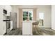 Well-lit kitchen features white cabinets, stainless appliances, breakfast bar, and backyard access at 215 Carova Bnd, Apex, NC 27539