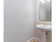 Powder room featuring a pedestal sink with elegant fixtures, decorative mirror, and modern lighting at 218 W Barbee Chapel Rd, Chapel Hill, NC 27517