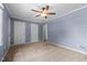 Bedroom features blue walls, ceiling fan, and multiple doors for access at 2216 Hoskins Rd, Burlington, NC 27215