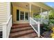 Inviting front porch with brick steps and white railings, complemented by the home's yellow siding and green shutters at 2216 Hoskins Rd, Burlington, NC 27215