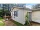 Side exterior view showing neutral siding, an exterior door, and wooded backyard at 2396 Spring Valley Rd, Henderson, NC 27537