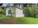 Exterior side view showcasing the home's siding, surrounded by green lawn and trees at 2396 Spring Valley Rd, Henderson, NC 27537
