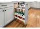 A pull out spice rack is located in the white kitchen island with shaker style cabinets and hardwood flooring at 245 Tumbling River Dr, Wendell, NC 27591