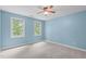 Bright bedroom featuring light blue walls, plush carpeting, and natural light from two windows at 297 Curragh Cv, Fuquay Varina, NC 27526