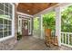 Inviting front porch showcasing stone accents, a wooden rocking chair, and a stylish front door with decorative wreath at 297 Curragh Cv, Fuquay Varina, NC 27526