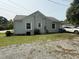 Rear view of a gray home with gravel driveway, grassy area, and an attached carport at 306 W Canary St, Dunn, NC 28334