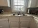 Close up of the sink with stainless steel faucet, white cabinets and decorative backsplash at 306 W Canary St, Dunn, NC 28334