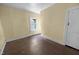 A simple bedroom with hardwood flooring, one window, and an open doorway at 312 W Front St, Oxford, NC 27565