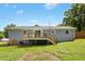 Back exterior view of gray home with a wooden deck, a grassy backyard, and mature trees at 4021 Chaucer Dr, Durham, NC 27705