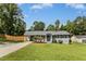 Landscaped home featuring a carport and driveway, surrounded by mature trees at 4021 Chaucer Dr, Durham, NC 27705