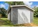 A gray, wooden detached garage with a white door sits outside with trees in the background at 4021 Chaucer Dr, Durham, NC 27705
