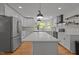 Bright kitchen with white cabinets, a large island with pendant lighting, and stainless steel appliances at 4259 Old Faison Rd, Knightdale, NC 27545