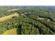 Aerial view highlights the property's secluded location amidst vast, lush forest and clear skies at 4964 Stafford Mill Rd, Liberty, NC 27298