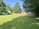 Spacious backyard showing a large grassy area, privacy fence and mature trees creating a serene outdoor setting at 109 N Watauga Ave, Dunn, NC 28334