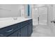 Bathroom features a blue vanity cabinet, glass enclosed shower, and white marbled floors in this modern home at 1124 Cedar Farm Trl, Fuquay Varina, NC 27526