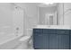 Bathroom features a blue vanity cabinet, tub, and white marbled floors in this modern home at 1124 Cedar Farm Trl, Fuquay Varina, NC 27526