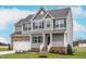 Charming two-story home showcasing stone accents, gray siding, and a welcoming front porch at 11640 International Dr, Middlesex, NC 27557