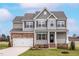 Charming two-story home showcasing stone accents, gray siding, and a welcoming front porch at 11640 International Dr, Middlesex, NC 27557