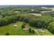 Wide aerial view of a home, barn, and multiple outbuildings with expansive forestry and bordering fields at 1167 John D Winstead Rd, Roxboro, NC 27574