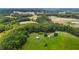 High-angle aerial view captures a red barn, adjacent house, and verdant pastures, accented by forests at 1167 John D Winstead Rd, Roxboro, NC 27574
