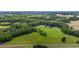 Expansive aerial view of a property featuring lush greenery, a red barn, and a charming home at 1167 John D Winstead Rd, Roxboro, NC 27574