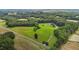 Lush aerial perspective revealing a red barn and pond, complemented by forests and green pastures at 1167 John D Winstead Rd, Roxboro, NC 27574