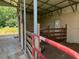 Barn interior with a stall, metal rafters, and concrete floor, providing a functional agricultural space at 1167 John D Winstead Rd, Roxboro, NC 27574