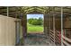 Inside the barn, metal beams frame a view of a grassy field and wooden fence at 1167 John D Winstead Rd, Roxboro, NC 27574