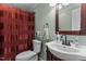 Bathroom featuring a toilet, dark brown wood vanity with sink, and a red shower curtain at 1167 John D Winstead Rd, Roxboro, NC 27574