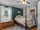 Bedroom with a four-poster bed, dark green accent wall, hardwood floors, and bright natural light at 1167 John D Winstead Rd, Roxboro, NC 27574