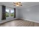 A cozy bedroom featuring a ceiling fan, light gray walls and wood-look flooring, plus windows for natural light at 1167 John D Winstead Rd, Roxboro, NC 27574