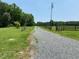 Gravel driveway leading to a gated property with fencing and green pastures, promising privacy and rural charm at 1167 John D Winstead Rd, Roxboro, NC 27574