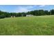Expansive grassy field leading to a charming single-story home and red barn in the distance at 1167 John D Winstead Rd, Roxboro, NC 27574