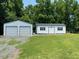 Newly constructed white storage building with two roll-up garage doors and a secondary shed with double doors at 1167 John D Winstead Rd, Roxboro, NC 27574