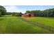 Picturesque view of a fenced pasture leading to a vibrant red metal barn at 1167 John D Winstead Rd, Roxboro, NC 27574