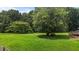 Expansive green yard with mature trees and a charming wooden deck, perfect for outdoor enjoyment at 1167 John D Winstead Rd, Roxboro, NC 27574