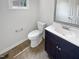 Well-lit half bath with a toilet, dark vanity, and neutral tile flooring under a window at 120 Point Harbor Dr, Cary, NC 27519