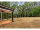 Covered back patio shows concrete flooring, dark wooden pillars, and a ceiling fan overlooking a large backyard at 125 Oswego Dr, Louisburg, NC 27549
