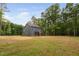 Expansive backyard shows lush green grass surrounded by mature trees and a two-story home with blue siding at 125 Oswego Dr, Louisburg, NC 27549