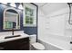 Bright bathroom with modern fixtures, an accent wall, and a tub with shower combo at 125 Oswego Dr, Louisburg, NC 27549